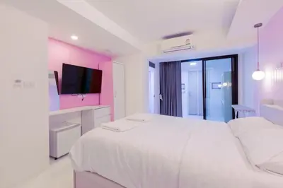 a white room with a large bed and a tv at 24 degree hotel & hostels in Bangkok
