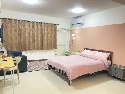 a bedroom with a bed and a table and a couch at La Maison 230 in Ban Khlong Samrong
