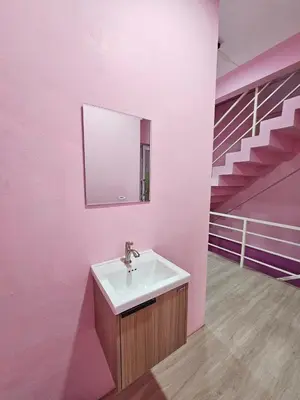 a bathroom with a sink and a pink wall at Hostel In The City in Pom Prap