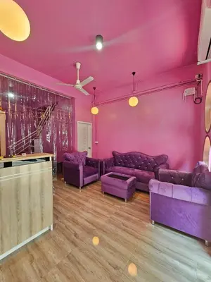 a living room with purple furniture and a pink wall at Hostel In The City in Pom Prap
