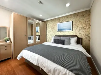 a bedroom with a large bed and a wall at Upscale Expansive 2BR - Ultra Fast Wifi - Phrom Phong in Bangkok
