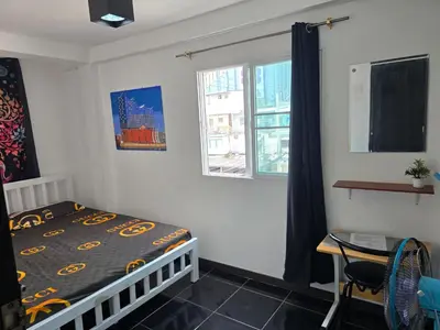 a bedroom with a bed and a desk and a window at Jatujak Bangkok guesthouse R 03-06 in Sathani Bang Su