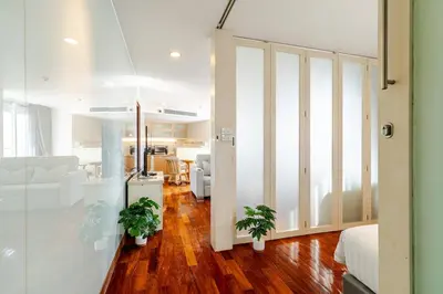 a living room with two potted plants on a wooden floor at 2Br, Good view, BTS Chitlom, BKK in Bangkok