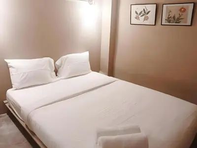 a bed with white sheets and pillows in a room at Rest Inn China Town - Yaowarat BKK in Samphanthawong