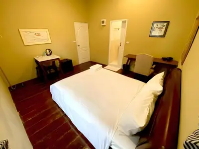a bedroom with a white bed and a table at Rest Inn China Town - Yaowarat BKK in Samphanthawong
