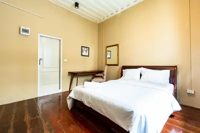 a bedroom with a large white bed and a table at Rest Inn China Town - Yaowarat BKK in Samphanthawong