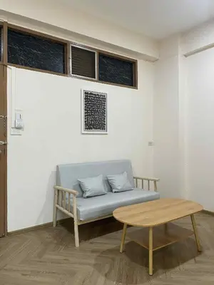 a couch in a room with a table and windows at Dime Rama III in Bangkok