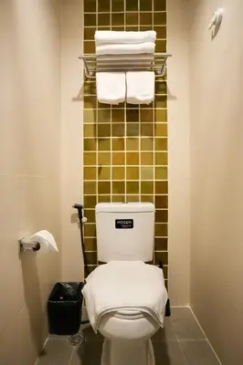a bathroom with a toilet with towels on a rack at Nivas Wanit 3BR 1SFB Yaowarat MRT EntireHome 85SQM in Bangkok