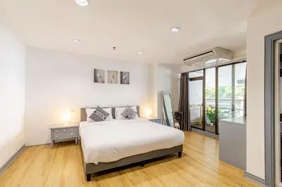 a white bedroom with a bed and a window at Cozy 2BR Apt in Central Bangkok 5 mins BTS 110 SQM by MattCo in Bangkok