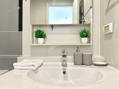 a white bathroom with a sink and two plants at Cosy & Bright 1 bedroom in Bangkok