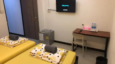 a room with two beds and a desk and a television at 731 Hostel Victory Monument in Sathani Sam Sen