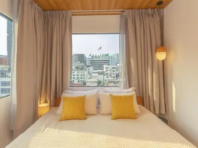 a bed with yellow pillows in a room with a window at 2 Bedrooms for 3 guest comfy home at heart of Silom - 7A in Bangkok