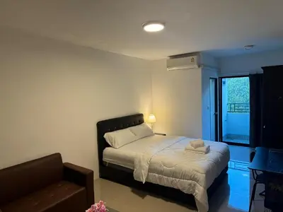 a bedroom with a bed and a chair and a window at Natthapimon in Bangkok Yai