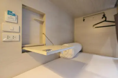 a small room with a table and a toilet at The Cube Hostel Silom in Bangkok