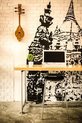 a desk with a computer on it in front of a wall at The Cube Hostel Silom in Bangkok
