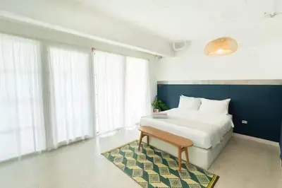 a bedroom with a bed and a rug and windows at The Local Heritage Loft Mansion in Bangkok