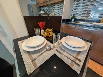 a table with plates and silverware on it in a kitchen at Cozy, Spacious 2-Bedder with City, Park View, Near Nana BTS in Bangkok