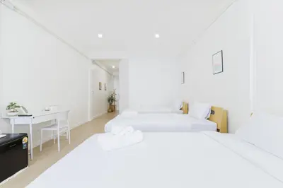a white bedroom with two beds and a table at A Townhouse 100m from BTS Bangchak in Phra Khanong