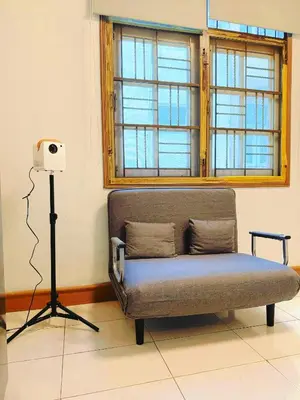 a couch in front of a window with a camera on a tripod at Regalohome Br in Bangkok