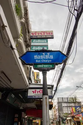 a street sign on a pole in front of a building at Skutan-MTB Sutthisan in Bangkok