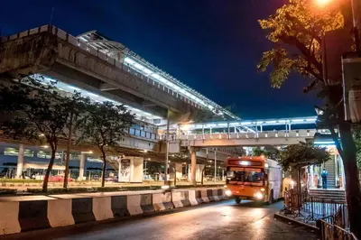 a bus driving down a street under an overpass at night at Skutan-MTB Sutthisan in Bangkok