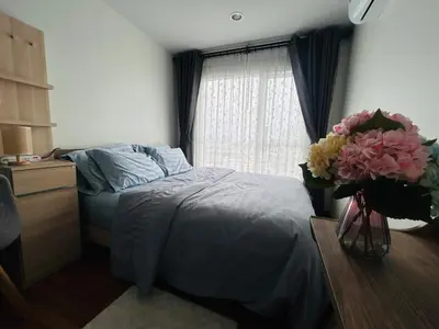 a bedroom with a bed and a vase of flowers at Charming condo 5min walk to MRT near DMK,Chatuchak in Bangkok