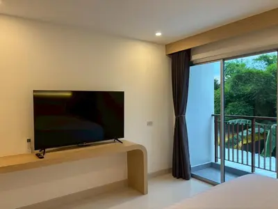 a bedroom with a flat screen tv and a balcony at Luna Residence in Ban Bang Phai