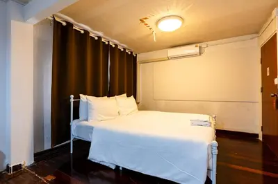 a bedroom with a white bed and a black curtain at Stay On Sukhumvit Soi 11 - สเตย์ ออน สุขุมวิท 11 in Bangkok