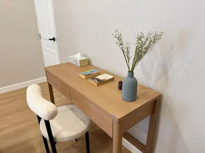 a wooden table with a vase of flowers and a chair at Vélin - Banthat Thong in Bangkok