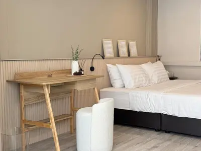 a bedroom with a bed and a table and a chair at Vélin - Banthat Thong in Bangkok