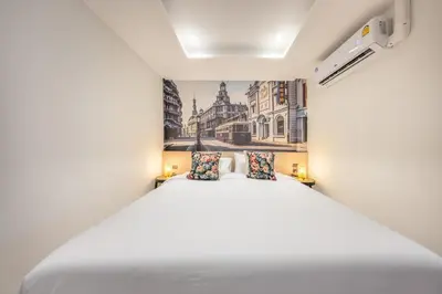 a bedroom with a white bed and a painting on the wall at U TOR Yaowarat - Bangkok Chinatown in Bangkok