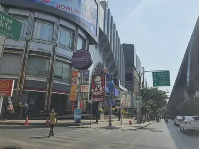 a woman crossing a street in front of a building at Luxury Japanese Onsen Reserve - Bangkok in Bangkok