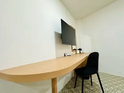 a wooden desk in a room with a black chair at The Cozy 77 in Bangkok