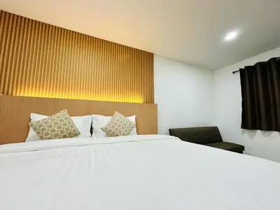 a bedroom with a large white bed and a chair at The Cozy 77 in Bangkok