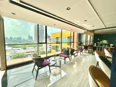 a waiting room with chairs and tables and large windows at Cosy apartment in Bangkok