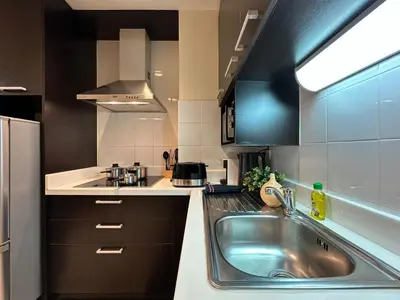 a kitchen with a stainless steel sink and black cabinets at Vibrant Modern 57 SQM - Ultra Fast WiFi - BTS Thonglor in Bangkok