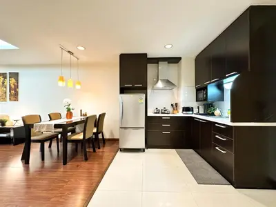 a kitchen with black cabinets and a table with chairs at Vibrant Modern 57 SQM - Ultra Fast WiFi - BTS Thonglor in Bangkok