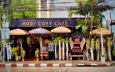a store with umbrellas on the side of a street at Rong-Pak BangRaMat by Modi Coff Café in Sathani Ban Chim Phali