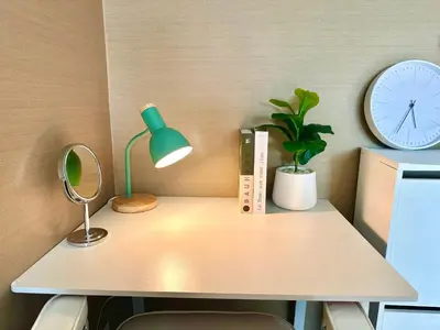 a desk with a lamp and a clock and a plant at Studio with view near Ekkamai in Bangkok