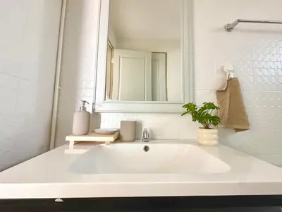 a white bathroom with a sink and a mirror at Cosy 2 bedrooms near Ekkamai in Bangkok
