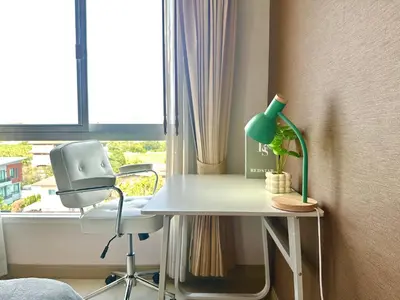 a desk with a green lamp and a chair in front of a window at Cosy 2 bedrooms near Ekkamai in Bangkok