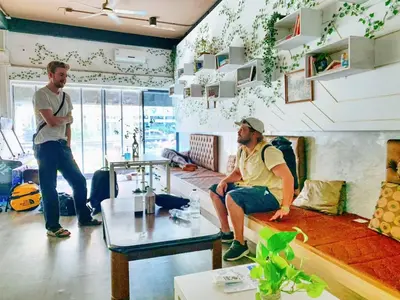two men are standing in a living room at SU SU khaosan hostels in Bangkok