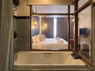 a bathroom with a tub with a bed in the mirror at Belivin'98 Sense of Pier Sathorn Residence in Bangkok