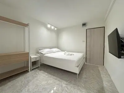 a white bedroom with a bed and a television at 95 Lodge in Bangkok
