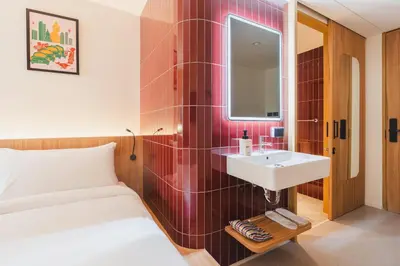 a bedroom with a bed and a sink and a mirror at VELA be Bangkok Siam in Bangkok