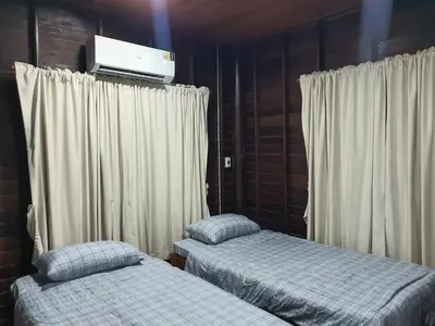 a bedroom with two beds and a tv on the wall at Baan Marrada Garden in Ban Pak Khlong Khwang