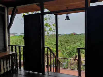 an open door to a porch with a view of a field at Baan Marrada Garden in Ban Pak Khlong Khwang