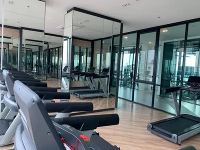 a gym with a row of cardio machines and glass walls at High Floor Luxury Studio with Great Views in Bangkok