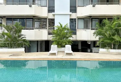 two chairs by a swimming pool in front of a building at Nana SkyView Retreat 2 Bedroom 2 Bath Nana BTS in Bangkok