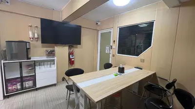 a room with a table and chairs and a tv at Golden mango home Youth hostel \u91d1\u8292\u679c\u4e4b\u5bb6\u9752\u5e74\u65c5\u820d in Bangkok